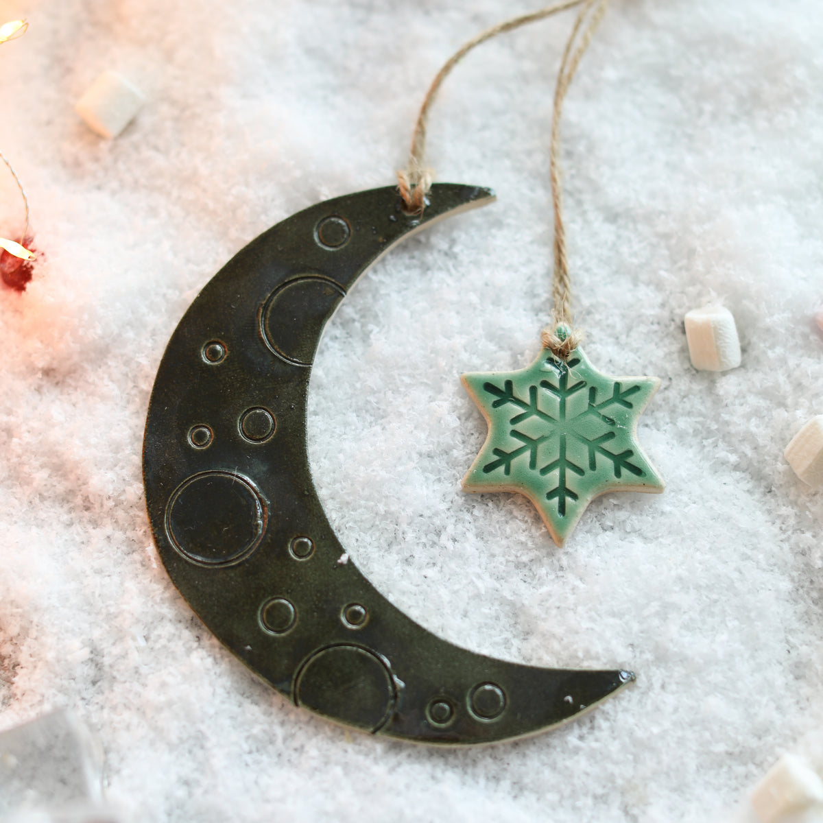 Decorative moon and star ornaments on a snowy background