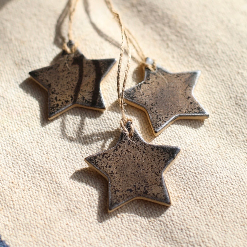 A shiny gold star made of ceramic with a twine hanging loop.