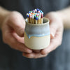 A ceramic pot filled with matches, featuring a colourful drippy glaze.