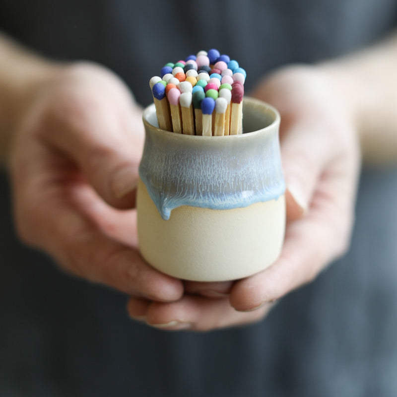 A ceramic pot filled with matches, featuring a colourful drippy glaze.