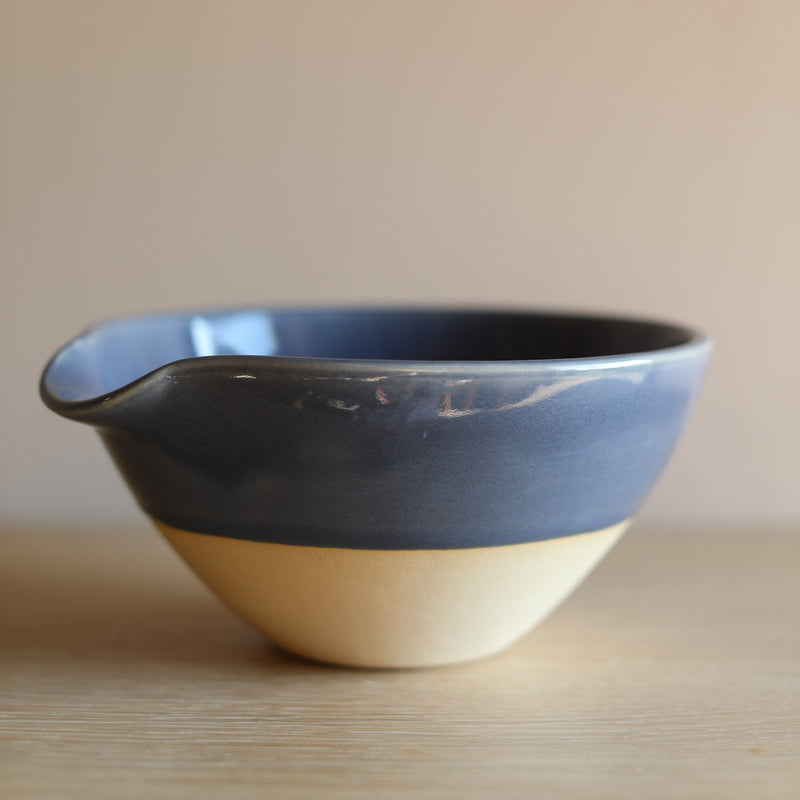 A ceramic bowl with an indented lip for easy pouring. 